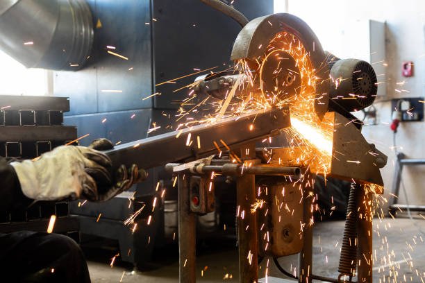 The man is cutting a metal box using cutting machine and the fire sparks splashes outside.